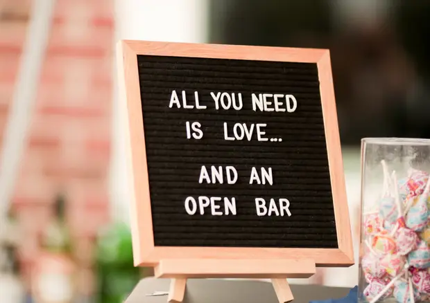 A wedding reception sign reading All You Need Is Love And An Open Bar