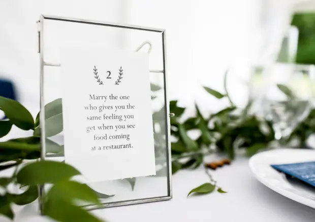 An elegant wedding table setting with greenery and a numbered place card