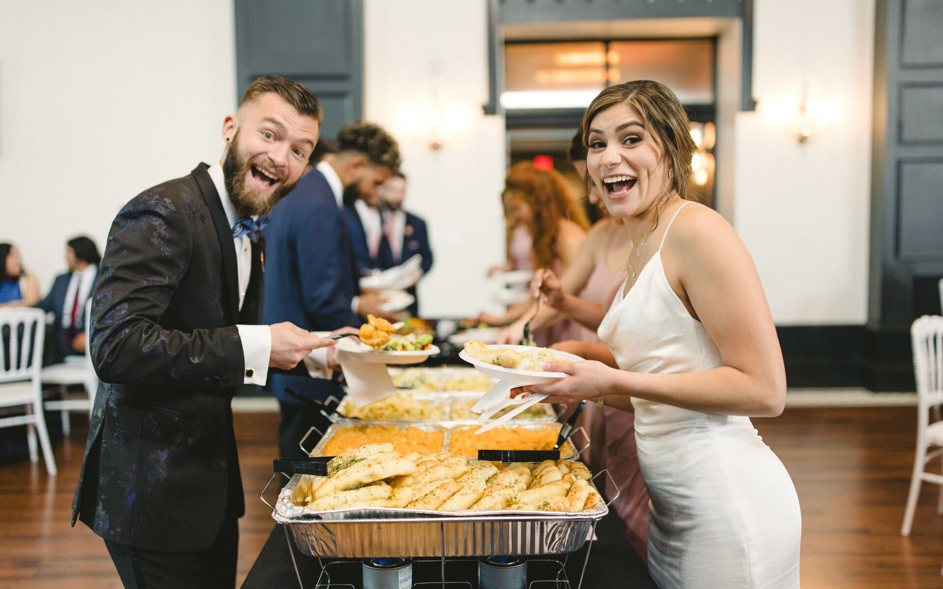 A bride and groom laughing together at their wedding buffet, catered by Nameless Catering